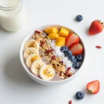 Eine bunte Frühstücks-Smoothie-Bowl mit Beeren, Banane, Granola, Chiasamen und frischen Früchten in einer hellen Schale.