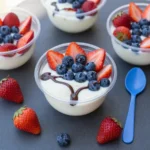 Eine Schüssel mit einem Açaí Bowl, garniert mit Banane, Beeren, Granola und Kokosraspeln auf hellem Hintergrund.