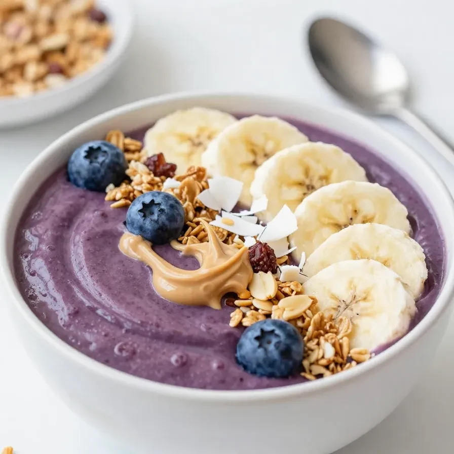 gesunde-acai-bowl mit banane 6 Eine gesunde Acai-Bowl mit Beeren, Banane, Granola und Kokosraspeln in einer hellen Schale.